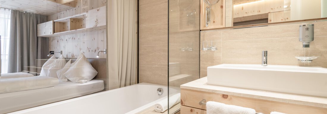 Badezimmer mit Badewanne - Blick zum Doppelbett - Hotel Olympia - Obergurgl 